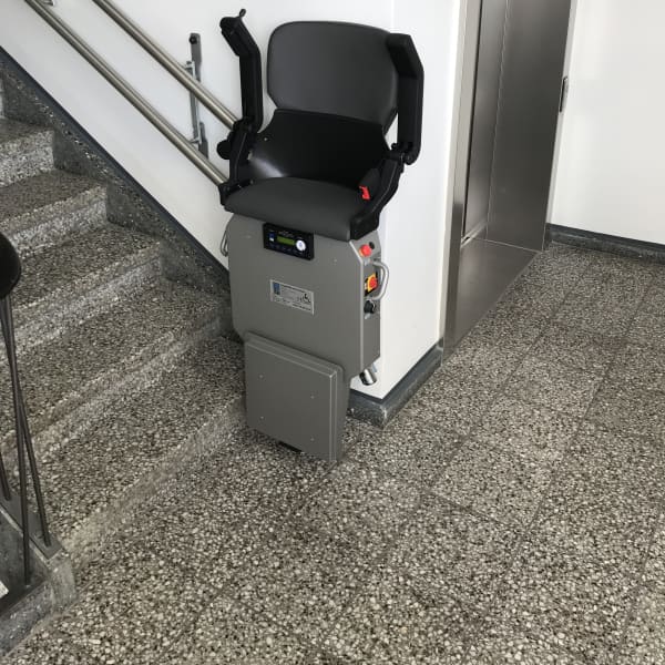Treppenlift zum Stehen in einem Treppenhaus.