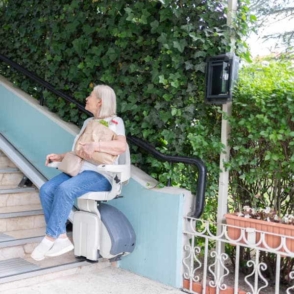 Frau fährt auf einem Außenlift die Treppe hoch.