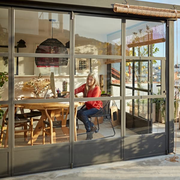 Ein Anlehnwintergarten mit Aluminiumrahmen und Glasfenstern und Ausblick über die Stadt.