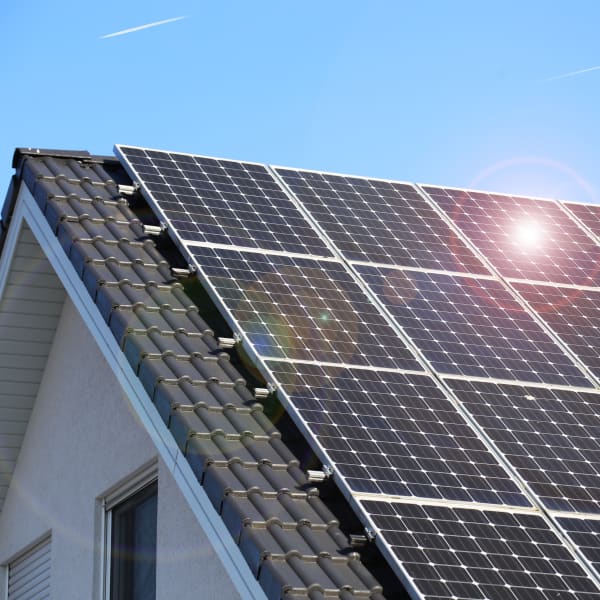 Solarmodule auf Hausdach bei blauem Himmel und Sonnenschein
