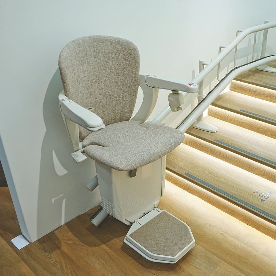 Sitzlift vor einer gewundenen und beleuchteten Treppe.