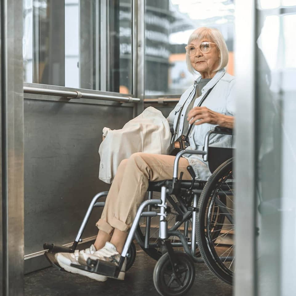 Ältere Frau im Rollstuhl im Fahrstuhl