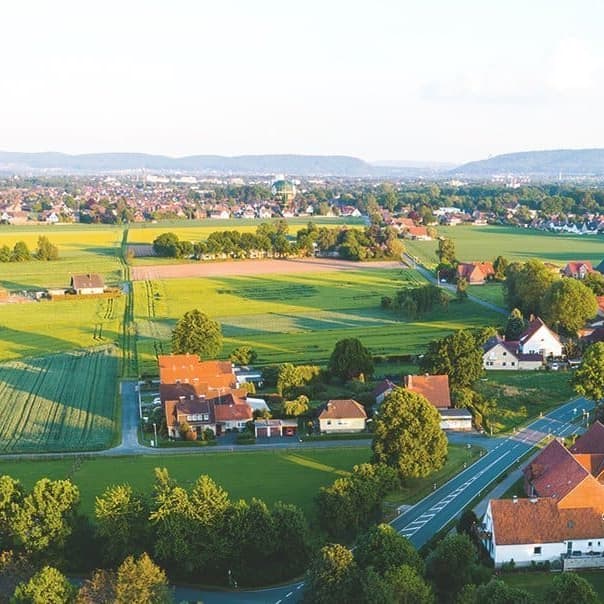 Luftaufnahme einer Ortschaft in Deutschland mit Wiesen bei Sonnenschein