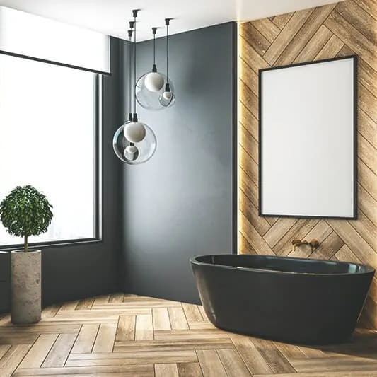 Zu sehen ist ein modernes Badezimmer mit hellem Holzboden, dunkler Wand und dunklen Amarturen und Badewanne.