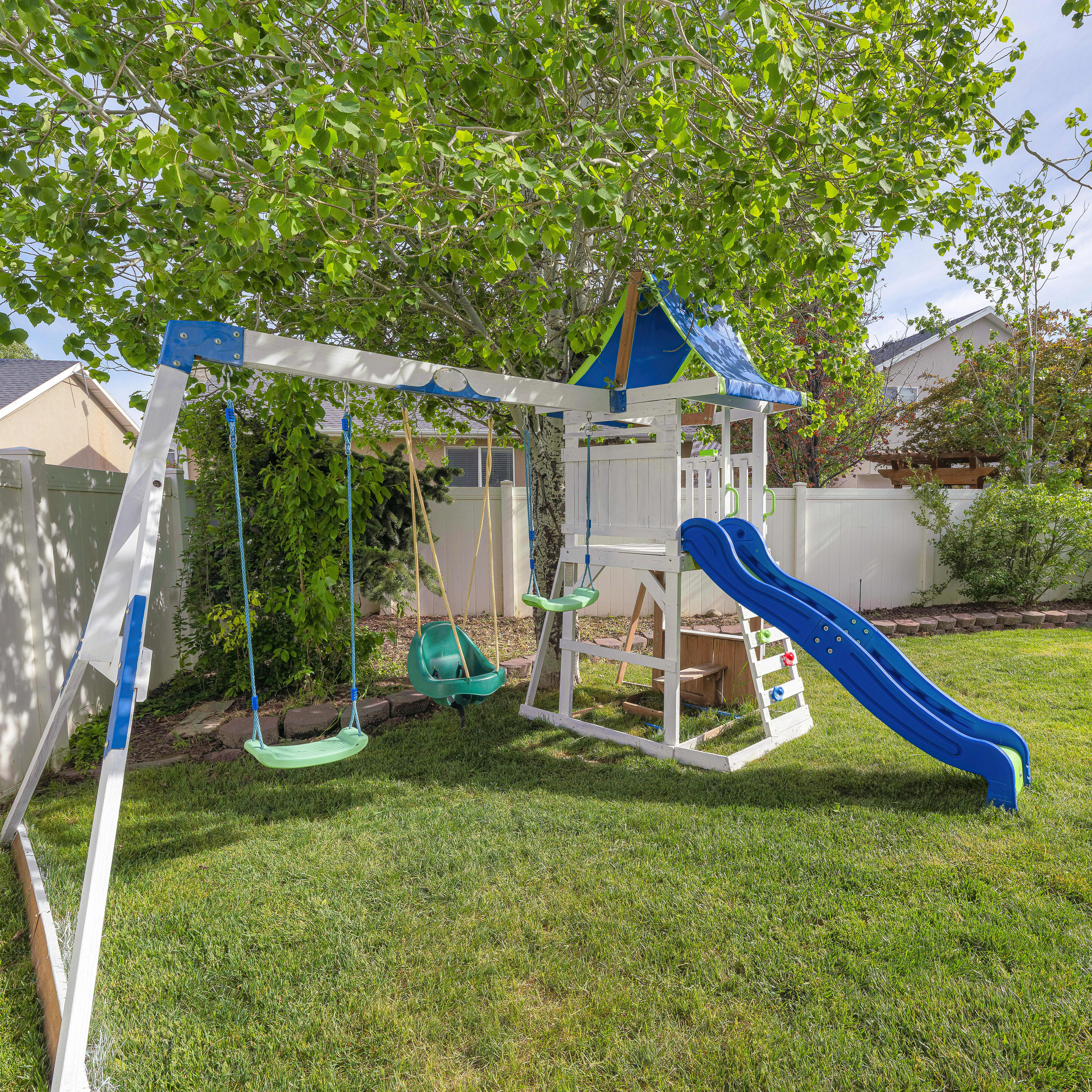 Garten mit einem Spielturm mit Rutsche und Schaukel.