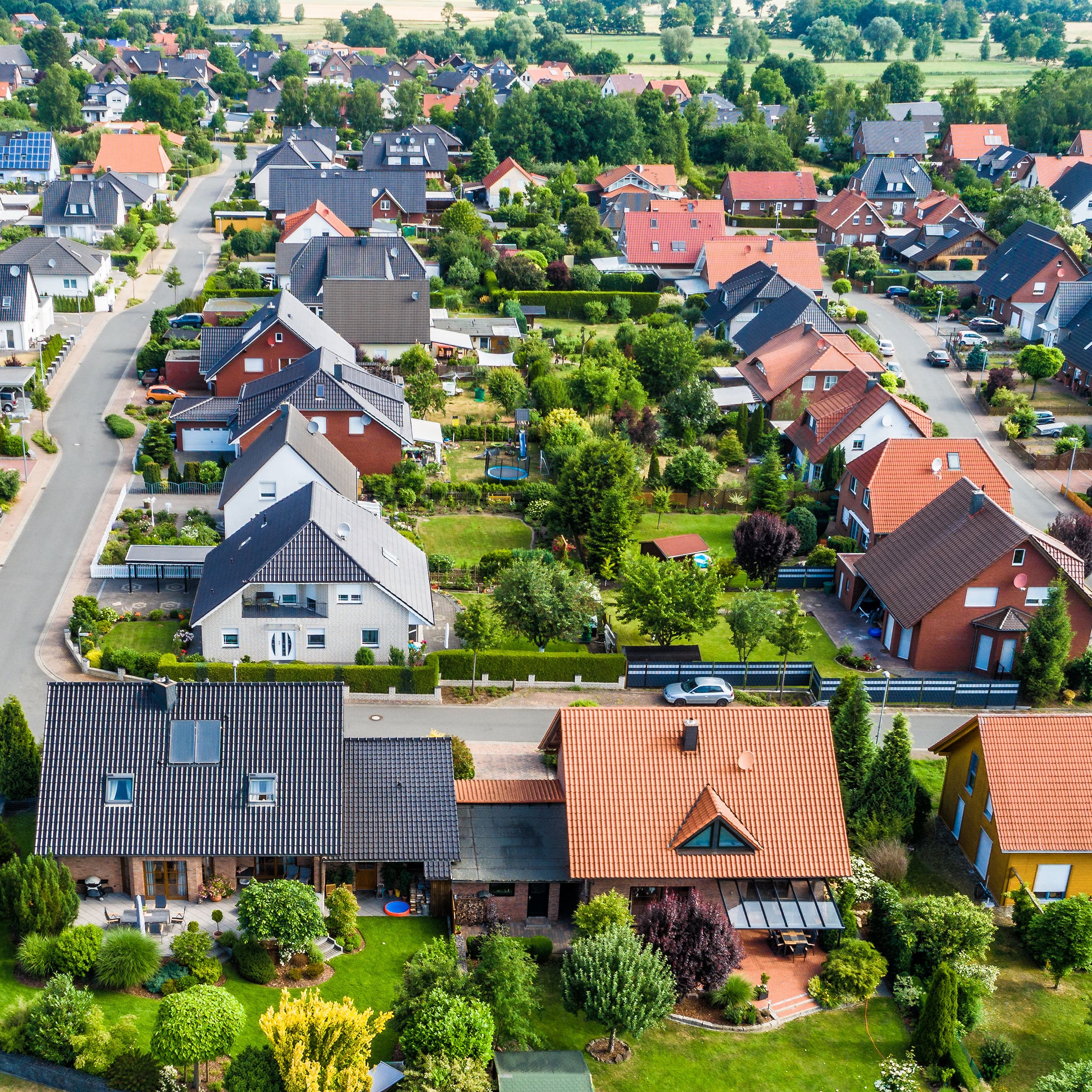 Luftansicht auf ein Neubaugebiet auf dem flachen Land in Norddeutschland zwischen Wald und Feldern und Wiesen