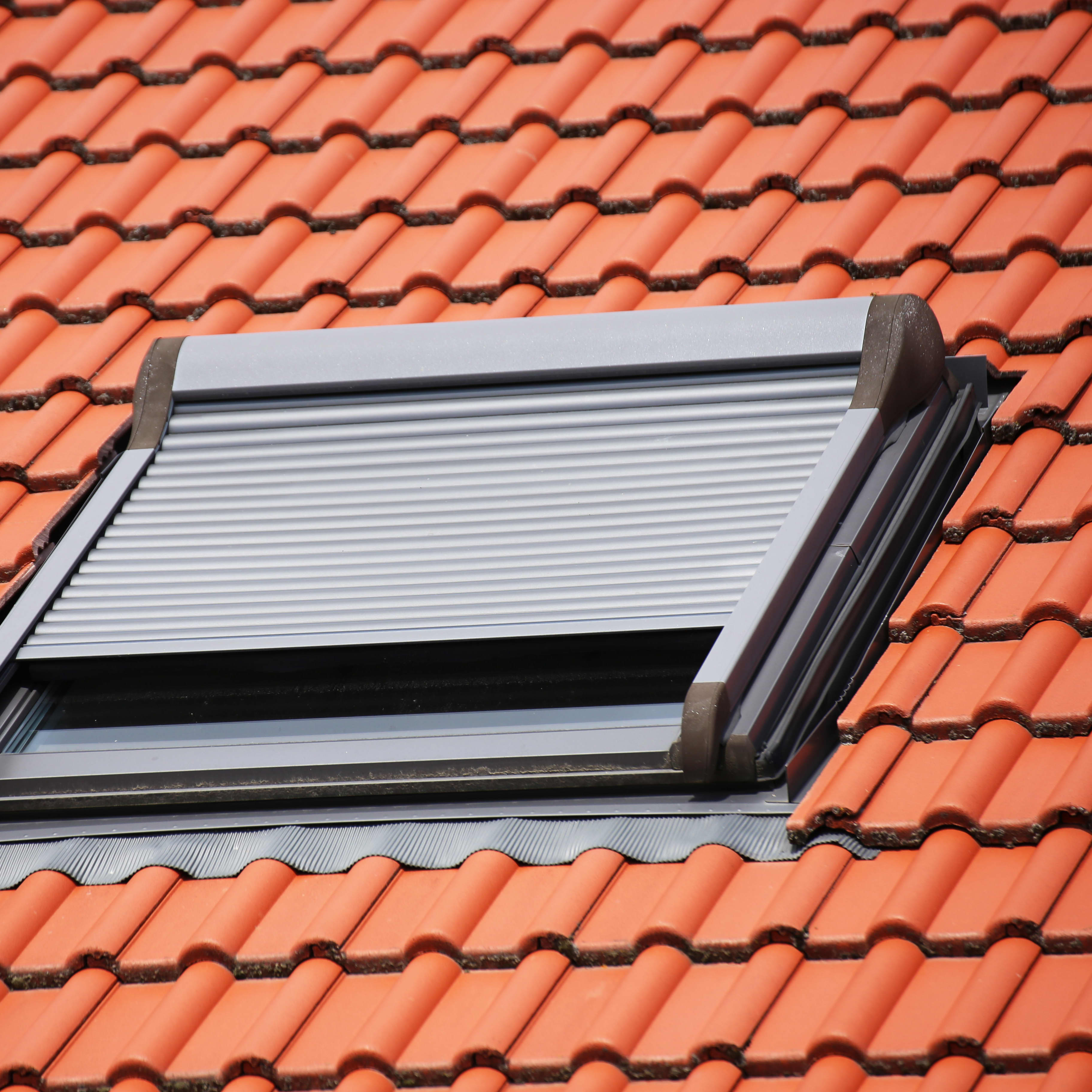 Dachfenster mit halb geschlossenem Rollladen.