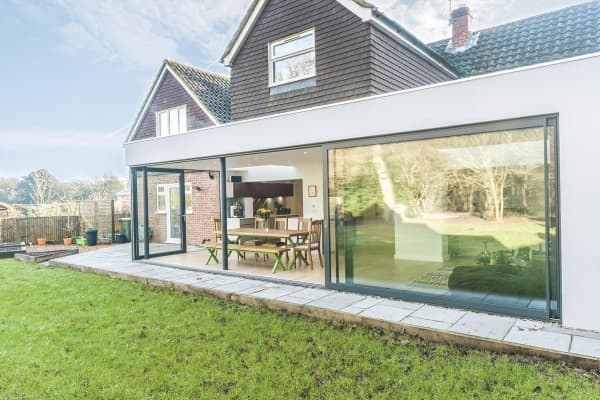 Hausfassade mit Schiebetür aus Verbundsicherheitsglas und bodentiefer Glasfront zum Garten