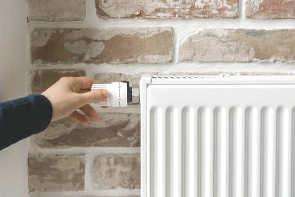 Frau dreht an Heizung