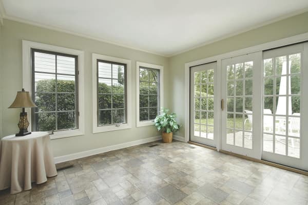 Heller Wintergarten mit großen Sprossenfenstern, Schiebetüren und Steinfliesenboden