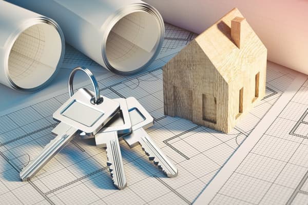 Grundrisse einer Immobilie mit Schlüsseln und Modellhaus aus Holz