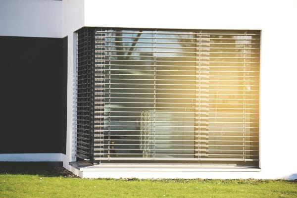 Sonnenschutz für Fenster: Modernes Eckfenster mit außenliegenden Jalousien bei Sonnenschein