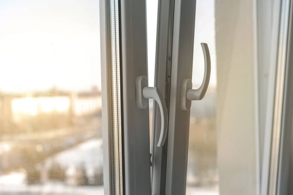 Geöffnetes Kunststoff-Fenster mit weißen Griffen bei Tageslicht