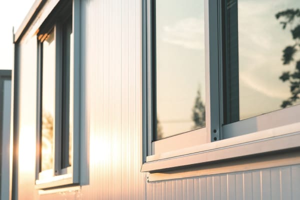 Moderne weiße Fensterfassade bei Sonnenuntergang – reflektierende Scheiben und Rahmen