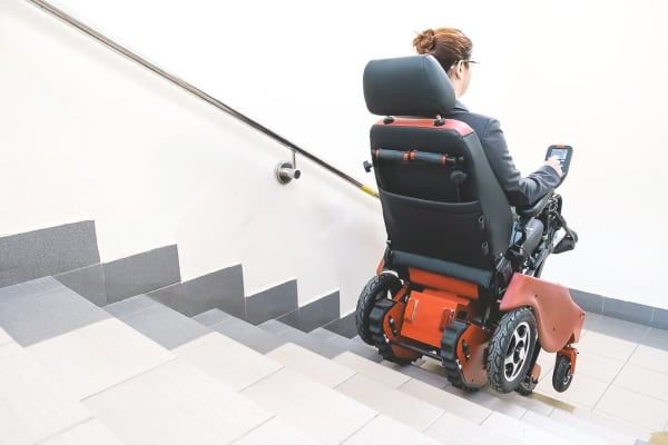 Frau fährt mit einer elektrischen Treppenraupe die Treppe hinauf