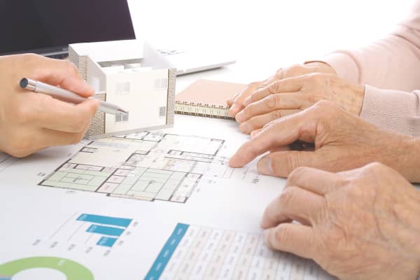 Hände älterer Personen zeigen auf einen Plan zum altersgerechten Umbau