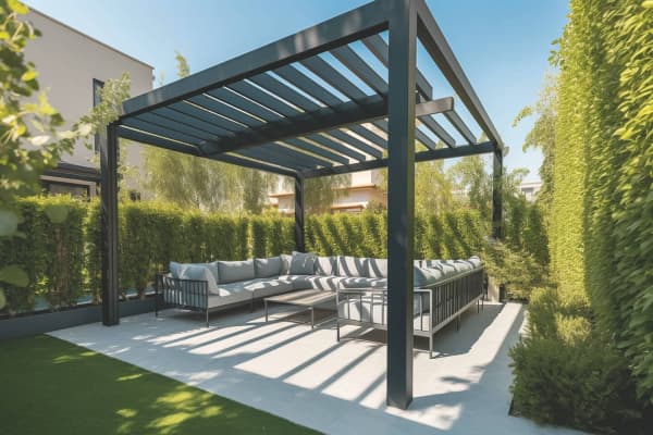 Freistehende Terrassenüberdachung mit vier Pfosten über einer gemütlichen Sitzecke.