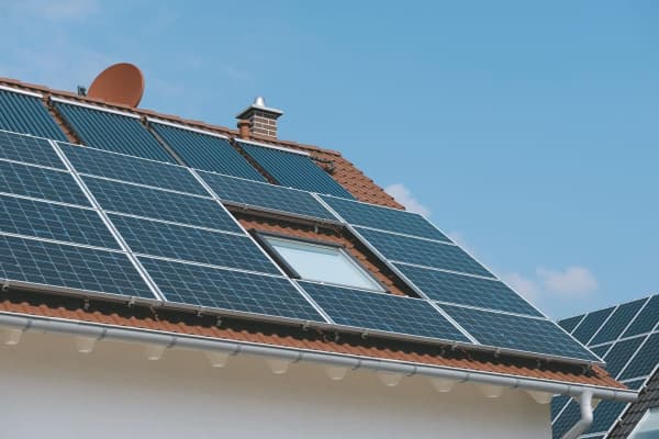 Einfamilienhaus mit großer Solaranlage auf dem Dach vor blauem Himmel