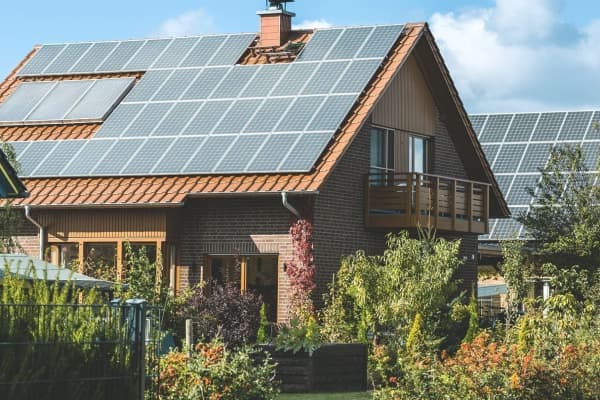 Zwei Wohnhäuser mit großer Solaranlage auf dem Dach in einem grünem Garten