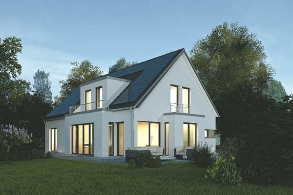 Ein Einfamilienhaus mit einer Solaranlage auf dem Dach am Abend, im Haus ist Licht an