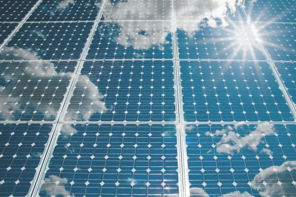 Mehrere Solarmodule nebeneinander, auf denen sich der Himmel spiegelt.