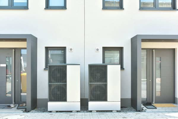 Zwei Wärmepumpen mit wenig Abstand vor einem Reihenhaus