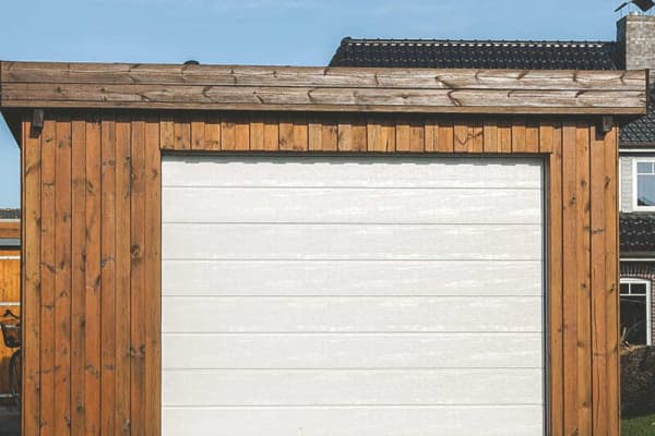 Fertiggarage aus Holz mit einem weißen Garagentor