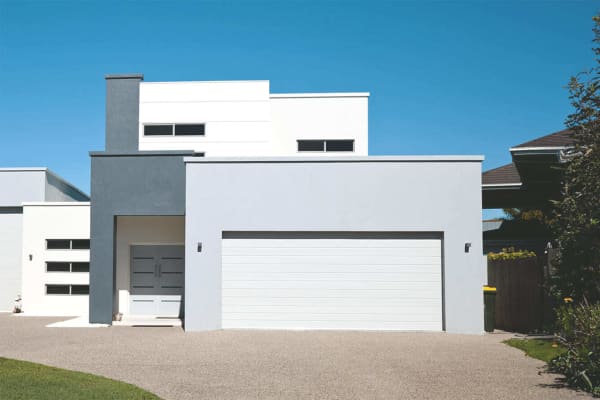 Betonfertiggarage mit breitem Sektionaltor vor modernem Wohnhaus