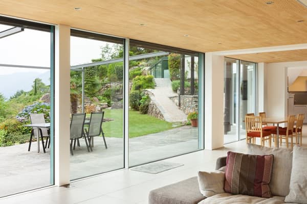 Rahmenlose Fensterfront mit Ausblick auf Garten und Terrasse