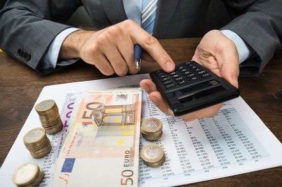 Ein Mann im Anzug berechnet die Beträge und zählt das Geld.