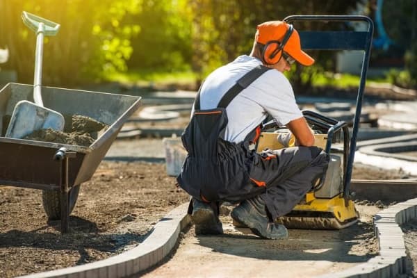 Handwerker bereitet Pflasterung eines Gartenwegs vor.