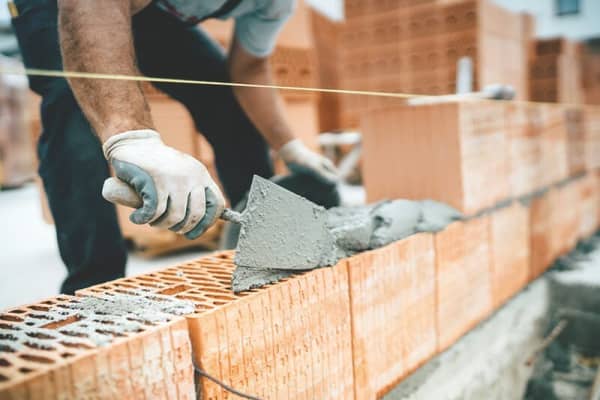 Maurer baut ein Massivhaus und streicht Zement auf Bausteine
