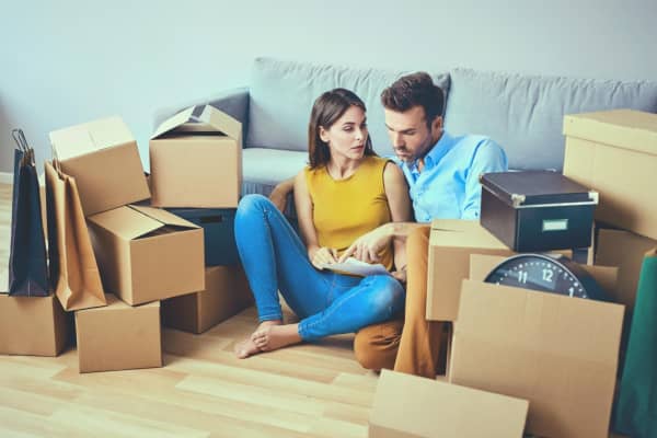 Paar sitzt gemeinsam zwischen Umzugskisten