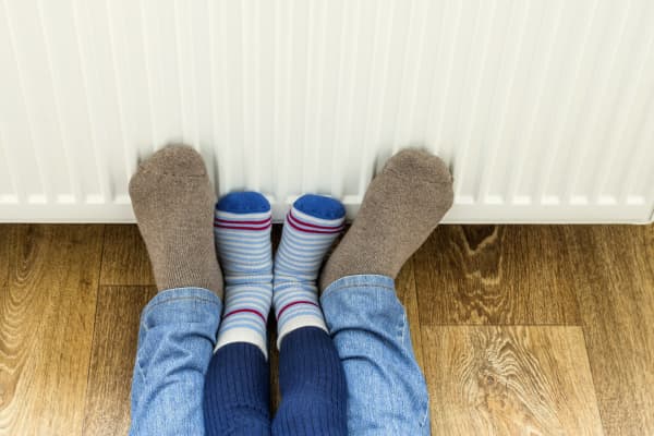 Mann und Kind wärmen Füße an Heizung