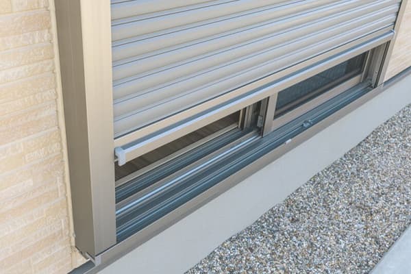 Halb geschlossener Außenrollladen vor bodentiefem Fenster mit Schiebeelement