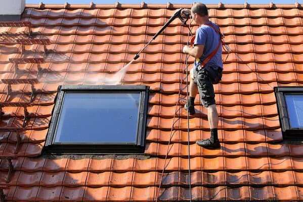 Dachfenster Reinigung von einem Handwerker auf einem roten Dach.