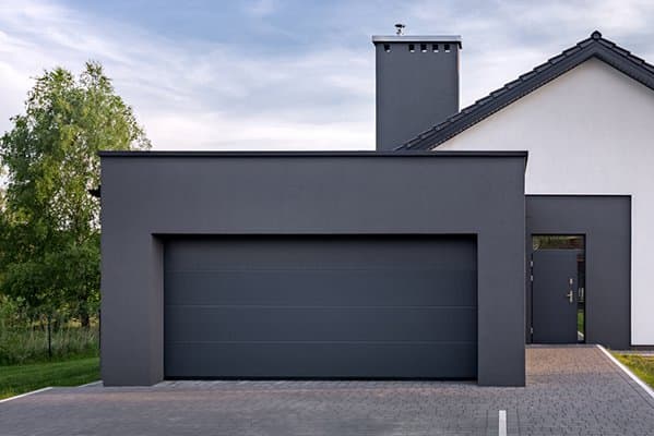 Betongarage mit breitem Tor vor einem Einfamilienhaus