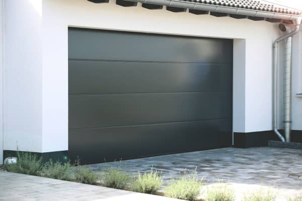 Garage mit unterschiedlichen Garagenmaterialien: Stahltor, Tonziegeldach und verputzte Wände