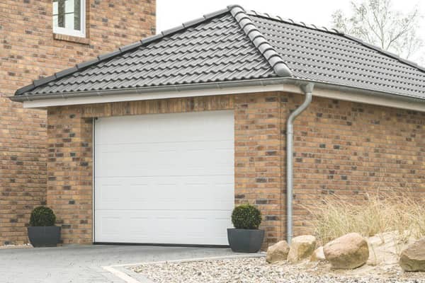 Freistehende gemauerte Garage aus rotem Backstein mit grauem Walmdach