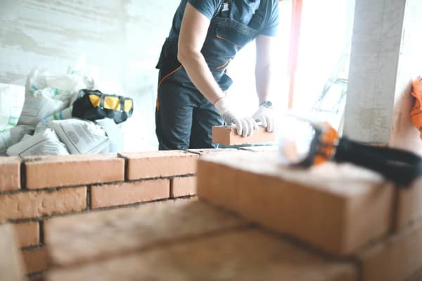 Mann mauert Wintergarten mit Ziegelsteinen