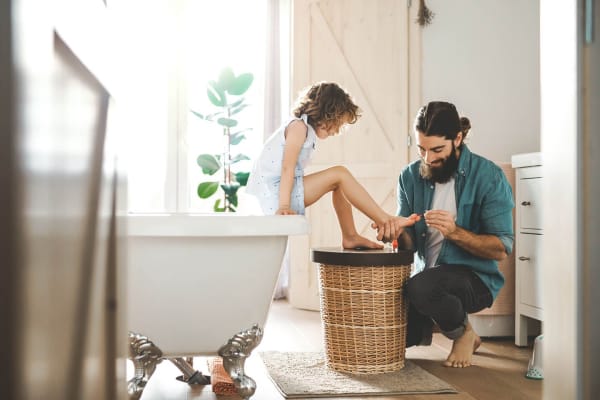 Vater lackiert seiner Tochter im Badezimmer die Fußnägel