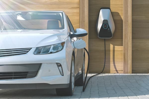 Auto steht vor Garage und wird aufgeladen über Wallbox