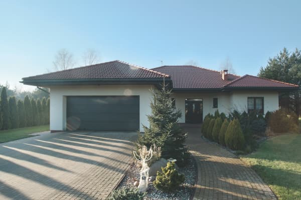 Großraumgarage mit Walmdach neben einem Wohnhaus.