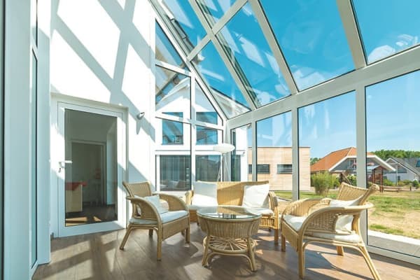 Moderner Wintergarten mit Glasdach und Rattanmöbeln
