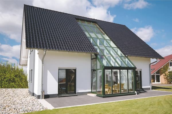 Wintergarten über zwei Etagen mit schräger Glasfassade, harmonisch integriert in das Dach eines modernen Einfamilienhauses.
