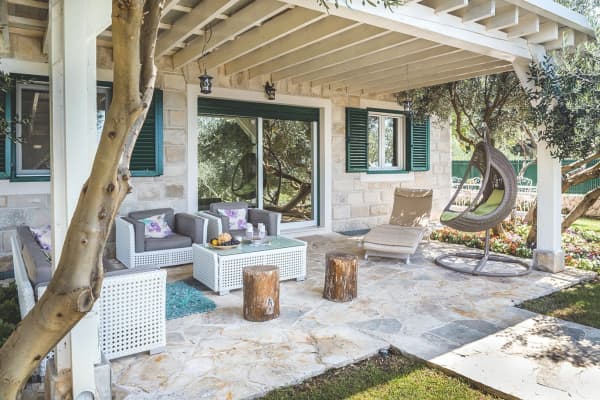 Eine weiß angestrichene Terrassenüberdachung aus Holz mit weißem Marmorboden