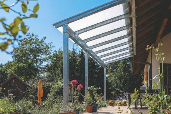Terrassenüberdachung aus Metall vor sommerlichem Garten