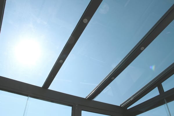 Moderne Wintergarten-Verglasung mit großen Glasflächen und schmalen Rahmenprofilen mit Blick in den Himmel.