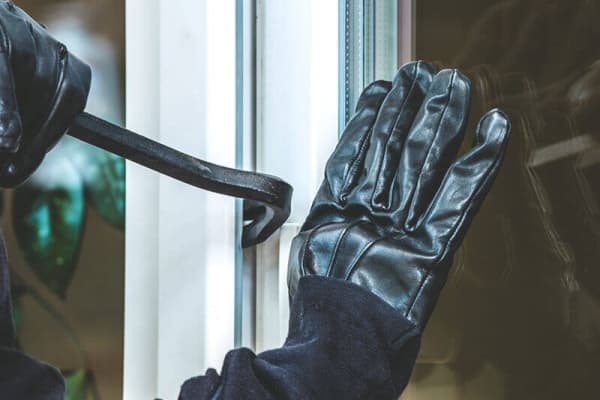 Einbruch mit Brecheisen an Fenster – Nahaufnahme mit Handschuhen