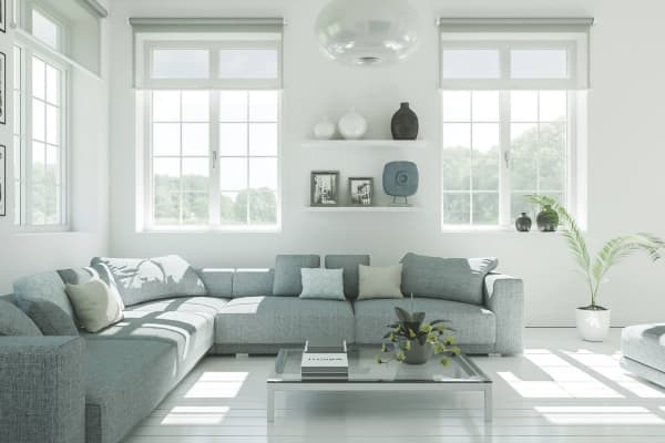 Helles Wohnzimmer mit grauer Eckcouch, großen Schallschutzfenstern und Glas-Couchtisch